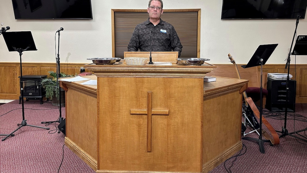 Pastor Kenny Batson stands at the pulpit of Grace Fellowship Church on Nov. 16, 2023, in El Dorado Springs, Mo. Batson was convicted of a series of crimes in the 1990s but became a Christian pastor after being released from prison. He was pardoned by Missouri Gov. Mike Parson. (AP Photo/David A.Lieb)